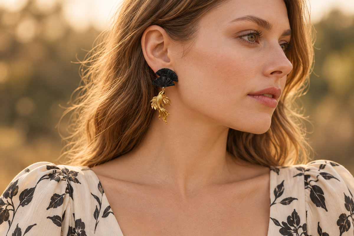 Black fan and golden koi earring paired with a cream botanical-print dress