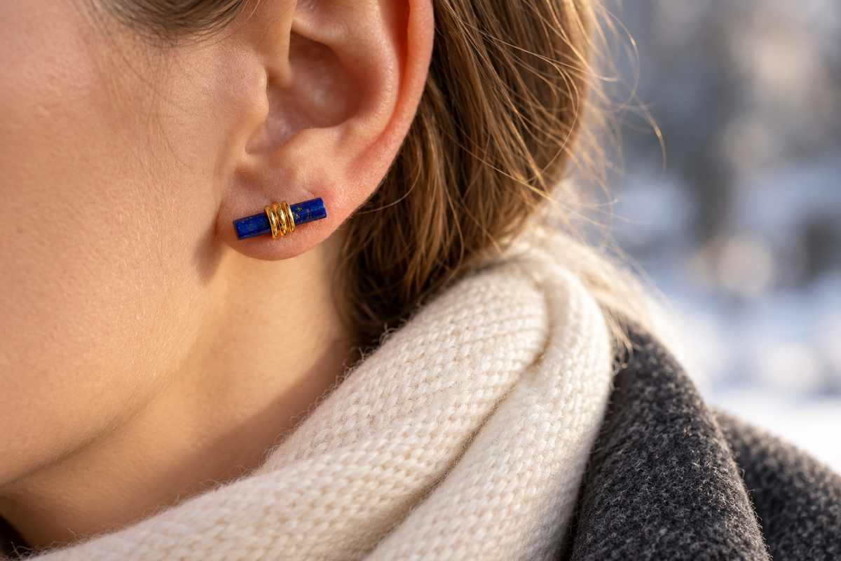 Blue bar stud worn with a low cream scarf and charcoal winter coat
