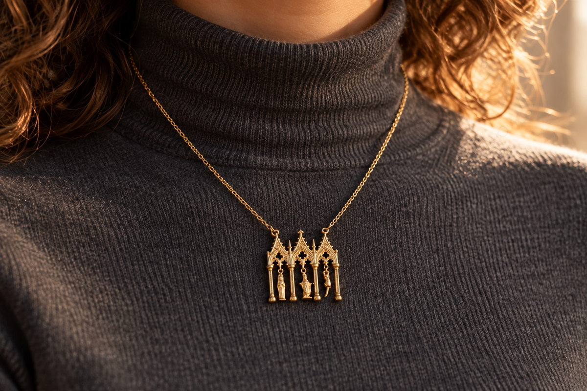 Gold architectural cat pendant styled over a smooth charcoal turtleneck